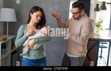 Junger Vater mit Baby und Frau, die zu Hause an postnataler Depression leidet Stockfoto