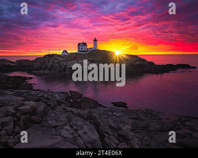 Aerial Nubble Lighthouse Sunrise - aus der Vogelperspektive auf einen wunderschönen dramatischen Himmel mit der aufgehenden Sonne hinter dem legendären Nubble Light. Stockfoto