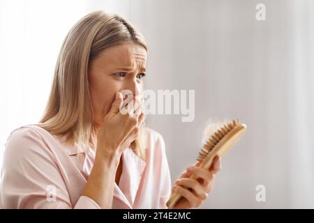 Schockierte Frauen Mittleren Alters, Die Einen Pinsel Voller Gefallener Haare Halten Stockfoto