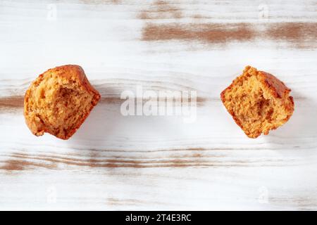 Gebrochene orangefarbene Muffins auf einem rustikalen Holzküchentisch, Flachbild-Lay-Shot mit Kopierraum Stockfoto