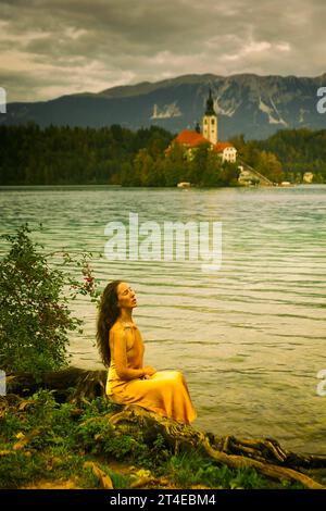 Frau in gelbem Kleid am Ufer des Bleder Sees, Slowenien II Stockfoto