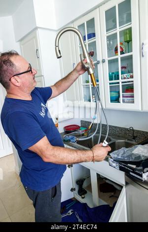 Miami Beach Florida, Handwerker Klempner, der Sanitär Küchenspüle repariert, neuen Wasserhahn installiert, Mann Männer männlich, Erwachsene, Bewohner, hispanisch lateinamerikanisch, ethn Stockfoto