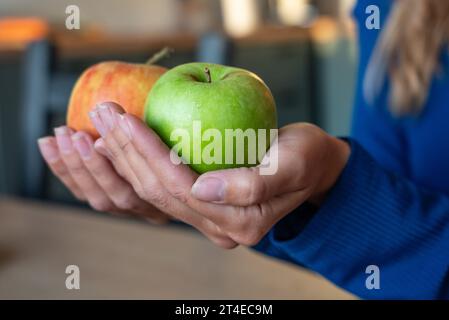 Die Frau hält Essen in der Hand. Das Mädchen hält einen Apfel. Äpfel in den Händen der Frau. Zwei grüne Äpfel Stockfoto