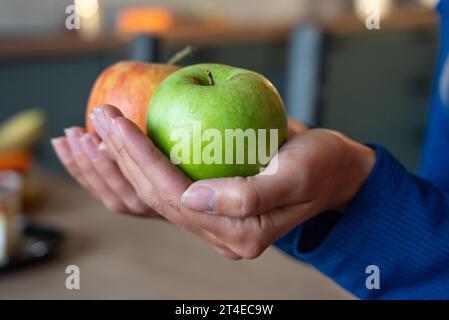 Die Frau hält Essen in der Hand. Das Mädchen hält einen Apfel. Äpfel in den Händen der Frau. Zwei grüne Äpfel Stockfoto