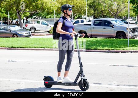 Miami Beach Florida, fahren elektrische Roller, tragen Sicherheitshelm Rucksack Straße, Frau Frauen weiblich, Erwachsene, Bewohner Stockfoto