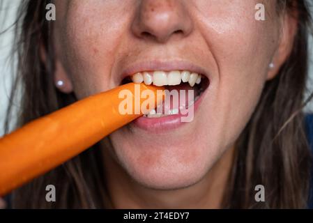 Frau isst Essen. Frau isst Karotten. Nahaufnahme eines Mädchens, das Karotten isst. Gesicht beim Essen von Karotten. Stockfoto