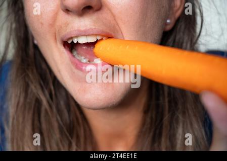 Frau isst Essen. Frau isst Karotten. Nahaufnahme eines Mädchens, das Karotten isst. Gesicht beim Essen von Karotten. Stockfoto