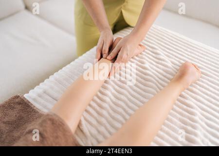 Nahaufnahme einer unerkennbaren Masseurin bei orthopädischen Beinübungen bei einer Teenager-Kundin, Prävention von Fersenschmerzen Stockfoto