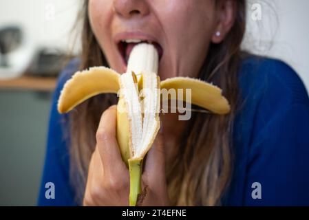 Frau isst Essen. Frau isst Banane. Nahaufnahme eines Mädchens, das Bananen isst. Gesicht beim Bananenessen Stockfoto