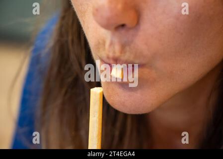 Frau isst Essen. Die Frau isst italienische grissini. Nahaufnahme eines Mädchens, das grissini isst. Gesicht beim Essen italienischer grissini Stockfoto