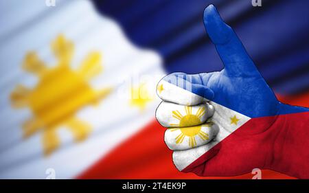 Hand mit Daumen nach oben in Übereinstimmung mit der philippinischen Flagge gemalt. Bild mit Markierungshintergrund unscharf, Kopierbereich Stockfoto