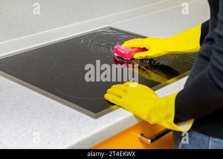 Eine Frau in Gummihandschuhen wäscht das Kochfeld in der Küche. Stockfoto