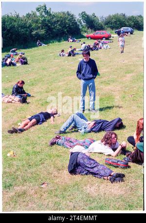 GLASTONBURY FESTIVAL, 1995: Am Montag nach dem Ende des Glastonbury Festivals, Pilton Farm, Somerset, England, 26. Juni 1995, warten die Menschen auf ihre Fahrt im „Busbahnhofbereich“ auf dem Parkplatz. 1995 feierte das Festival sein 25-jähriges Bestehen. In diesem Jahr gab es keine Pyramidenphase, da sie abgebrannt war. Foto: ROB WATKINS Stockfoto