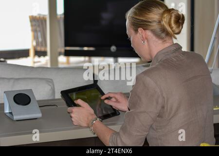 Seychellen, La Digue - 05. Oktober 2022: Frau, die zu Hause ein Tablet benutzt und auf den Bildschirm tippt Stockfoto