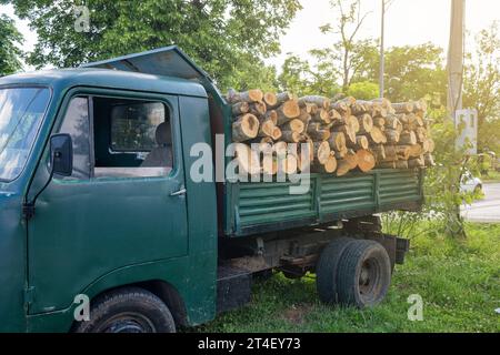 Kipper mit einer Leiche voller Brennholz. Lkw beladen mit Holzstämmen zur Lieferung für die Heizsaison. Brennholz für den Herd während der Stockfoto