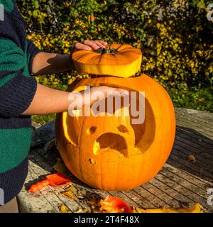 Kind, das Katzenmaske in Kürbis ausschneidet, Schweden, 31. Oktober 2023 Stockfoto