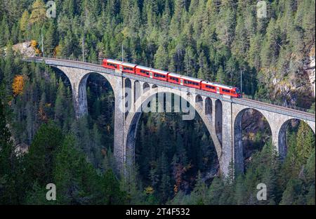 Davos Wiesen - Oktober 2023: Ein roter Personenzug überquert das berühmte Wiesener Viadukt auf der Bahnstrecke Davos – Filisur, dem höchsten Viadukt in s Stockfoto