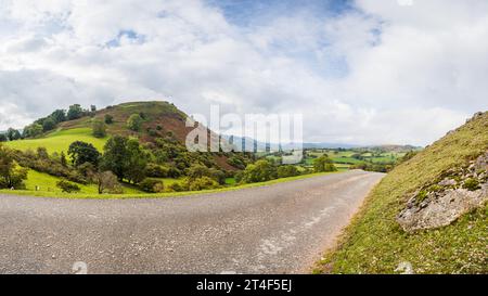 Die Ruinen von Castell Dinas Bran auf einem Hügel bei Llangollen in Wales hinter einer kurvenreichen Straße. Stockfoto