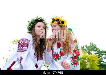 Mittsommer. Zwei Mädchen in slawischer Kleidung weben Zöpfe in der Nähe des Feuers. Stockfoto