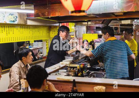 Tokio, Japan - 11. April 2023: Nachtszene in einer Straßenküche in Tokio, Japan, mit nicht identifizierten Menschen. Tokio hat eine berühmte Lebensmittelindustrie mit viel Stockfoto