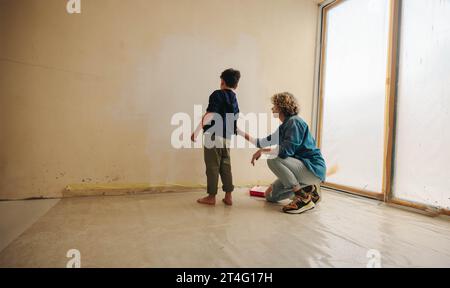 Der kaukasische Junge und seine Mutter malen und renovieren kreativ ihr Haus. Ein kleines Kind, das mit seiner Mutter eine Familienaktivität macht, um ihre Ho zu verbessern Stockfoto