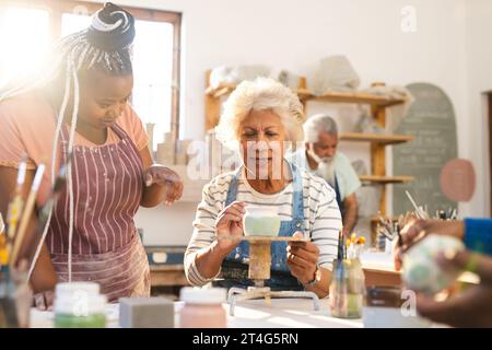 Zwei verschiedene Töpferinnen verglasten Tonkrug und diskutieren im Töpferstudio Stockfoto