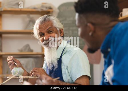 Zwei verschiedene männliche Töpfer verglasten Tonkrug und diskutierten im Töpferstudio Stockfoto