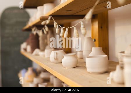 Töpferschalen und Tassen in Regalen im Töpferstudio Stockfoto