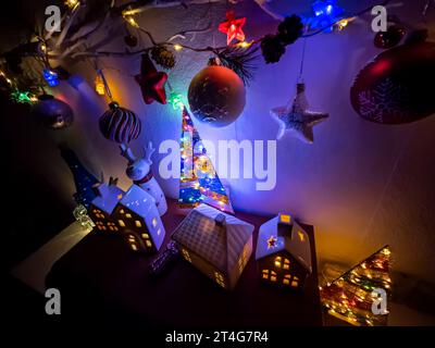 Neujahrsdekoration mit weihnachtsbaumkugeln am Zweig und beleuchteten Spielzeughäusern. Stockfoto