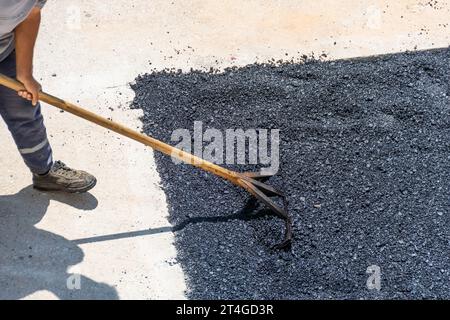 Auf dem Bürgersteig, Straßenarbeiter, die frisch gelegten, heißen Asphalt nivellieren, aus der Vogelperspektive Stockfoto