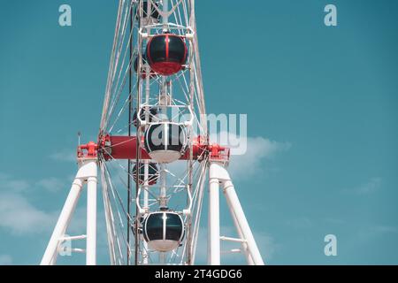 Rot-weiße Kabinen enden, Seitenansicht auf einem weißen Riesenrad gegen den Himmel Stockfoto