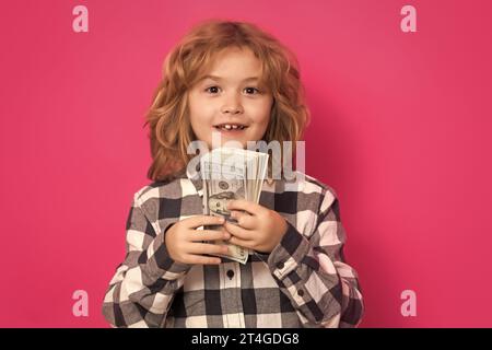 Ein Kind, das viele hundert Dollar isoliert auf rosa rotem Hintergrund hat. Stockfoto