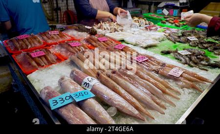 Die Leute bezahlen für frische Meeresfrüchte. Verschiedene Tintenfische, Garnelen und Fisch auf dem Fischmarkt Stockfoto