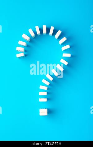 Domino-Fliesen in Form eines fraglichen Zeichens auf blauem Hintergrund Stockfoto
