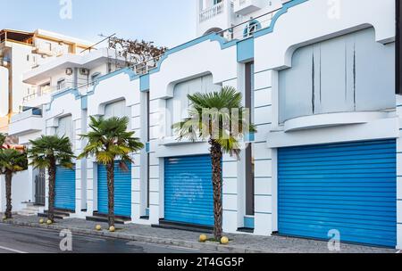 Blaue Türen von geschlossenen Garagen auf dem gemeindewohnsitz. Reihe von Selbstlagereinheiten mit über-Kopf-Klappen. Reihe von Garagentoren im Bereich der Stadthäuser. Stockfoto