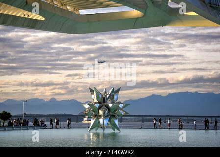 Ein Flugzeug, das über die gepuffte Star II Skulptur auf der Wasseroberfläche des Museums of Tomorrow fliegt - Rio de Janeiro, Brasilien Stockfoto