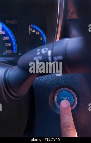 Drücken Sie mit dem Finger auf die Auto-Start-Taste. Umweltfreundliches Fahrkonzept Stockfoto