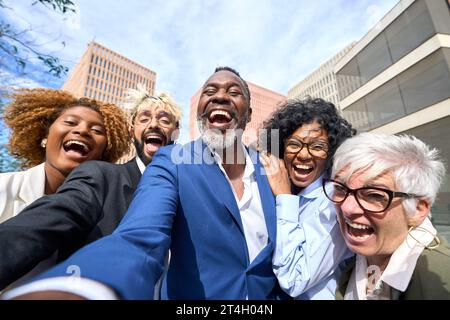 Glücklicher afrikanischer Geschäftsmann, der ein Selfie macht und mit multiethnischen Kollegen lacht Stockfoto
