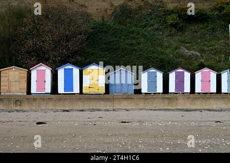 Eine idyllische Strandszene mit mehrfarbigen Strandhütten, die in einer Reihe angeordnet sind. Stockfoto