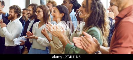 Fröhlich zufriedenes Publikum, das während einer Geschäftskonferenz oder eines Seminars fröhlich applaudiert. Stockfoto