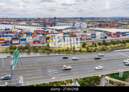 Luftaufnahme des Verkehrs auf einem Freeway vor Containerhaufen auf einem Kai bei Docklands in Melbourne, Victoria, Australien Stockfoto