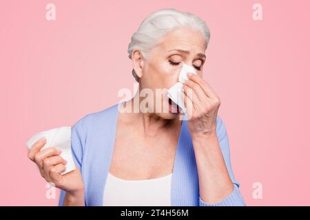 Grauhaarige alte schöne weiße Frau, die zwanglos an Fieber, Husten, Niesen leidet. Isoliert über violettem Pastellhintergrund Stockfoto