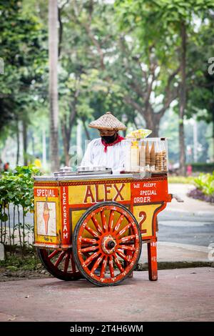 Ein Eisverkäufer arbeitet von seinem klassischen, wunderschön gestalteten Wagen in Rizal Park, Ermita, Manila, den Philippinen. Stockfoto