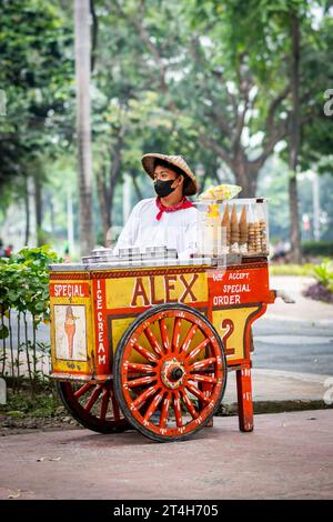 Ein Eisverkäufer arbeitet von seinem klassischen, wunderschön gestalteten Wagen in Rizal Park, Ermita, Manila, den Philippinen. Stockfoto