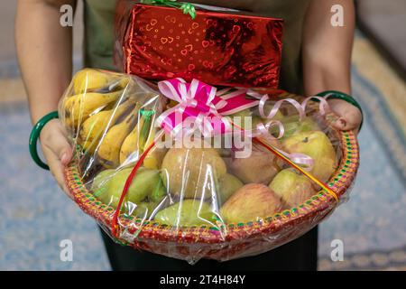 Geschenkverpackung mit verschiedenen Früchten und Geschenkverpackung, die aus flachem Winkel zur Hand gehalten wird Stockfoto