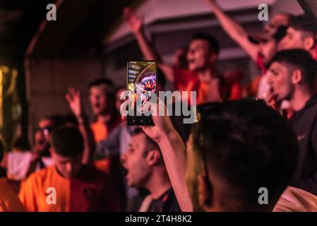 Istanbul, Türkei. 24. Oktober 2023 Galatasaray-Fußballfan mit Handy, während er vor dem Champions-League-Spiel gegen den FC Bayer Lieder singt Stockfoto