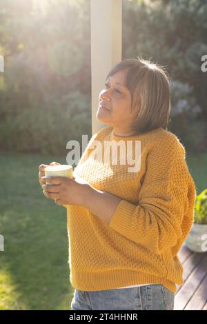 Glückliche Frau, die im Garten Tee trinkt Stockfoto