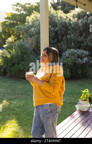 Glückliche Frau, die im Garten Tee trinkt Stockfoto