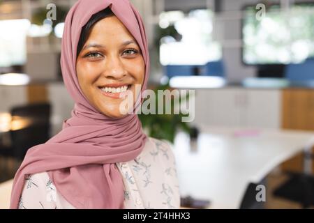 Porträt einer glücklichen birassischen Geschäftsfrau mit Hijab im kreativen Büro, Kopierraum Stockfoto