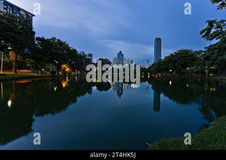 Lumphini Park bei Nacht mit Blick auf einen Teich und die Skyline dahinter Stockfoto